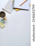 Flat lay, coffee cup, notebook and wireless keyboard on white table with copy space.