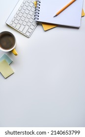 Flat lay, coffee cup, notebook and wireless keyboard on white table with copy space.