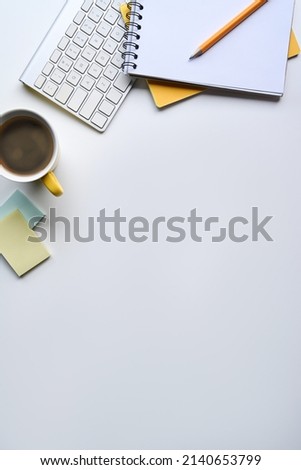Flat lay, coffee cup, notebook and wireless keyboard on white table with copy space.