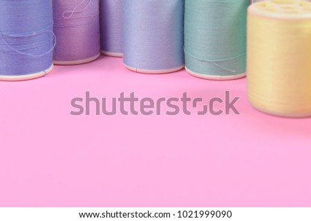 Flat lay of colored thread rolls for sewing on pink background, Sewing and needlework concept.