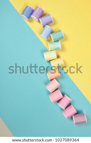 Flat lay of colored thread rolls for sewing on two tone background, Sewing and needlework concept.