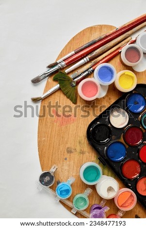 Flat lay of colorful paints, painting palette and brushes on white background, art, painting and hobby concept, top view, copy space.