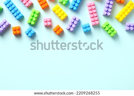Flat lay colorful plastic building blocks on pastel blue background. Baby educational toys concept.