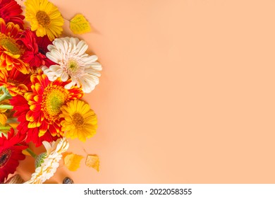 Flat Lay With Colorful Red Yellow Orange Autumn Flowers On Beige Warm Colored Background. Bright Fall, Thanksgiving Day Concept. Top View, Copy Space