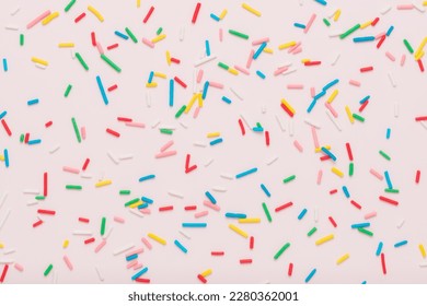 flat lay of colorful sprinkles over pink background, festive decoration for banner, poster, flyer, card, postcard, cover, brochure, designers.