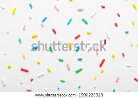 flat lay of colorful sprinkles over white background, festive decoration for banner, poster, flyer, card, postcard, cover, brochure