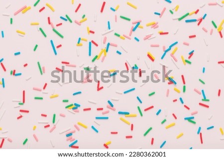 flat lay of colorful sprinkles over pink background, festive decoration for banner, poster, flyer, card, postcard, cover, brochure, designers.