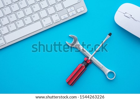 Flat lay of combination spanner or wrench, screwdriver, keyboard computer and mouse on blue background with copy space. Online support, customer care, after sales service and maintenance concept.