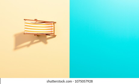 Flat Lay Of A Composed Miniature Of Beach Lounge Area With Deck Chair On The Colorful Surface