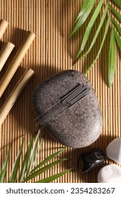 Flat lay composition with acupuncture needles on bamboo mat