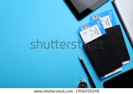 Flat lay composition with avia tickets and passports on light blue background, space for text. Travel agency concept