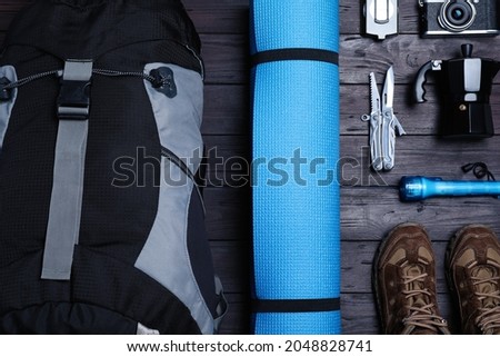 Flat lay composition with backpack and other different camping equipment for tourism on wooden background