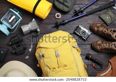 Flat lay composition with backpack and other camping equipment for tourism on wooden background