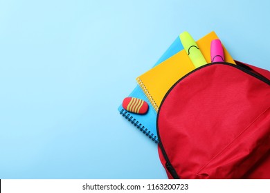Flat lay composition with backpack, school stationery and space for text on color background