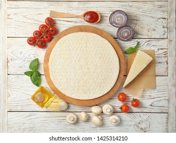 Flat Lay Composition With Base And Ingredients For Pizza On Wooden Table