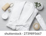 Flat lay composition with bathrobe and spa essentials on white wooden background