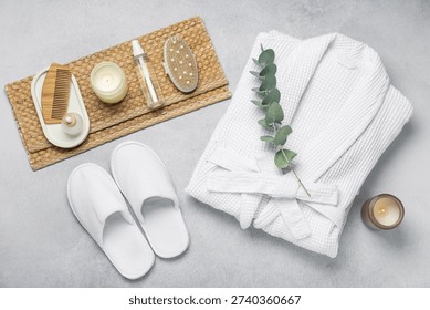 Flat lay composition with bathrobe and spa essentials on light grey background