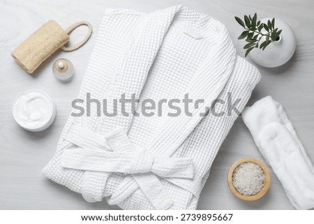 Flat lay composition with bathrobe and spa essentials on white wooden background