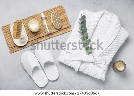 Flat lay composition with bathrobe and spa essentials on light grey background