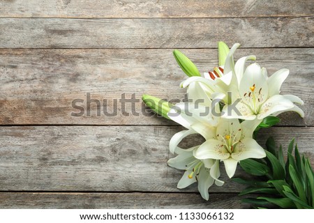 Flat lay composition with beautiful blooming lily flowers on wooden background