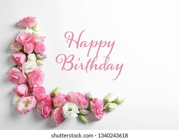 Flat lay composition with beautiful eustoma flowers and text Happy Birthday on light background