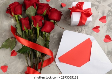Flat lay composition with beautiful red roses, love letter and gift box on light grey background. Valentine's Day celebration