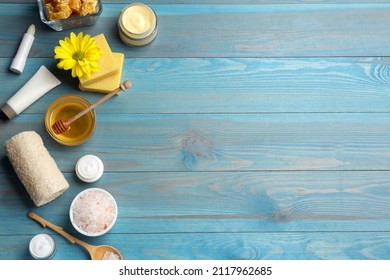 Flat lay composition with beeswax and cosmetic products on blue wooden table. Space for text