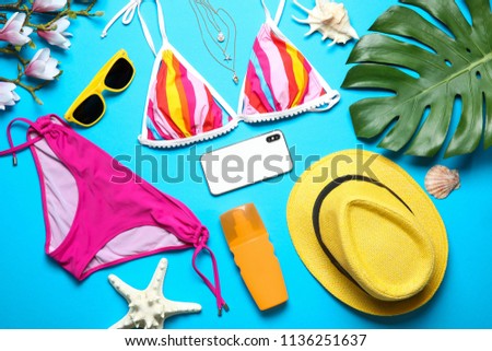 Flat lay composition with bikini, smartphone and beach objects on color background