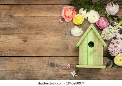 Flat lay composition with bird house and flowers on wooden background. Space for text