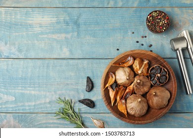 Flat lay composition with black garlic on blue wooden table. Space for text