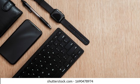 Flat lay composition with black pen, computer keyboard, smart watch, smartphone and leather wallet on a wooden surface. Business concept. Business people items. Free space for text. Stationery. 