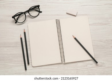 Flat lay composition with blank sketchbook on white wooden table. Space for text