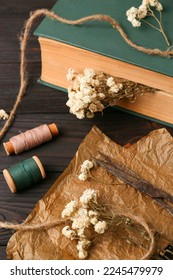 Flat lay composition of book with flowers as bookmark and scissors on wooden table