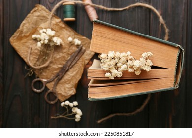 Flat lay composition of book with flowers as bookmark and scissors on wooden table