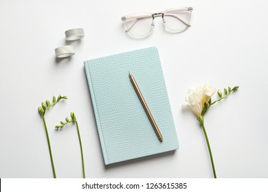 Flat lay composition with book, glasses and flowers on white background