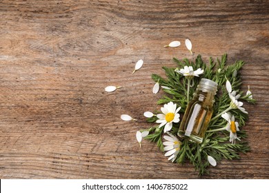 Flat lay composition with bottle of chamomile essential oil and space for text on wooden background