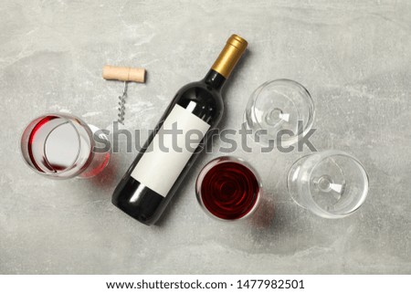 Flat lay composition with bottle and glasses of wine, corkscrew on grey background, copy space