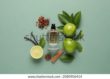 Flat lay composition with bottle of perfume and fresh citrus fruits on pale green background