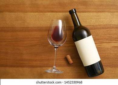 Flat lay composition with bottle of wine and elegant glass on wooden background. Space for text