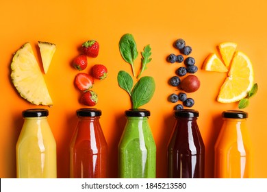Плоская композиция с бутылками вкусных соков и свежих ингредиентов на оранжевом фоне