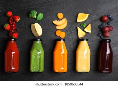 Flat lay composition with bottles of delicious juices and fresh ingredients on black table