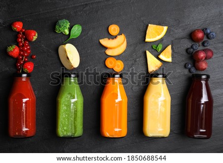 Flat lay composition with bottles of delicious juices and fresh ingredients on black table