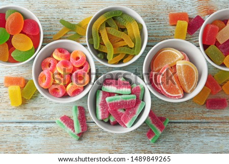 Flat lay composition with bowls of different jelly candies on wooden background