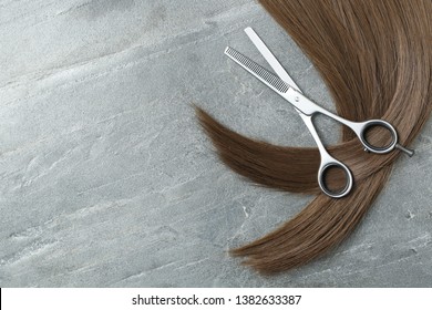 Flat Lay Composition With Brown Hair, Thinning Scissors And Space For Text On Grey Background. Hairdresser Service