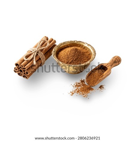 Flat lay composition of a bundle of cinnamon sticks with ground cinnamon spice in a vintage brass bowl and olive wood scoop.

