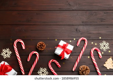 Flat lay composition with candy canes and Christmas decor on wooden table. Space for text