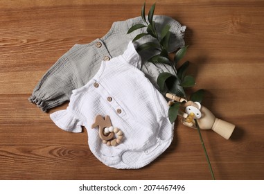Flat lay composition with children's clothes, toys and pacifier on wooden table