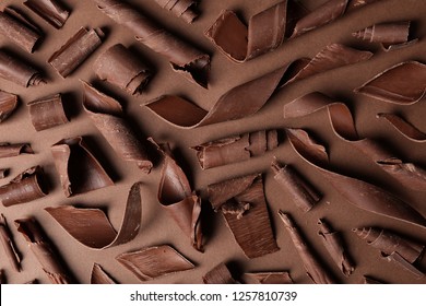 Flat lay composition with chocolate curls on color background