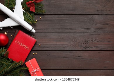 Flat lay composition with Christmas decorations and toy airplane on wooden background, space for text. Winter vacation