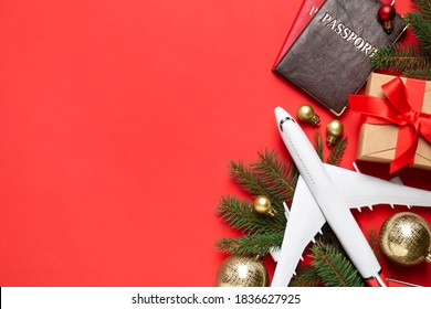 Flat lay composition with Christmas decorations, toy airplane and passports on red background, space for text. Winter vacation